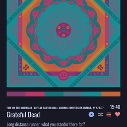Music player screen showing the Grateful Dead performing “Fire on the Mountain” live at Barton Hall, Cornell University, Ithaca, New York, on May 8, 1977. The album artwork features a colorful geometric mandala in teal, magenta, and orange with stylized skull motifs and the concert details around the border. The screen displays the current lyric: “Long distance runner, what you standin’ there for? Get up, get out, get out of the door...” along with playback controls and a progress time of 15:40.